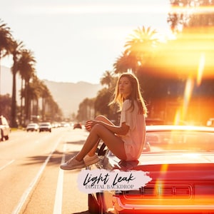 Könnte beinhalten: Eine Frau sitzt auf dem Heck eines roten Autos auf einer sonnigen Straße mit Palmen. Das Bild hat einen warmen, goldenen Farbton mit Lensflare-Effekten. Der Text "LIGHT LEAK DIGITAL BACKDROP" ist sichtbar.