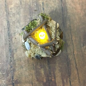 May include: A miniature campfire made of twigs and moss with a small LED light in the center, creating a warm glow.
