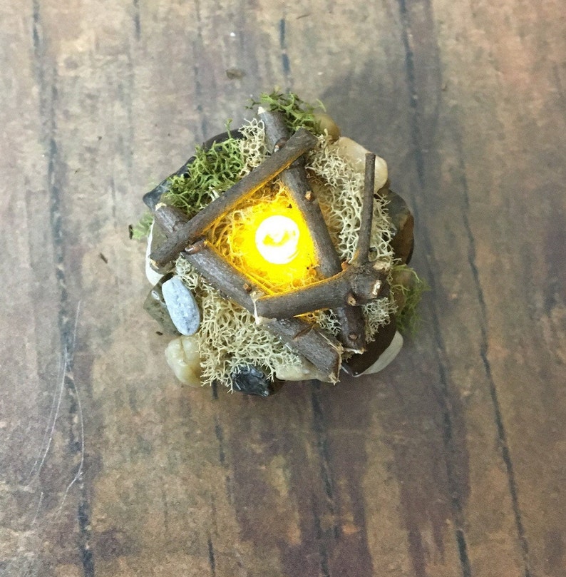 May include: A miniature campfire made of twigs and moss with a small LED light in the center, creating a warm glow.