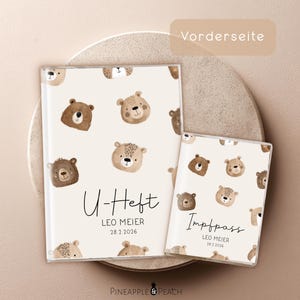 Könnte beinhalten: Zwei cremefarbene Baby-Aufnahmebücher mit einem sich wiederholenden Muster aus braunen Teddybärgesichtern. Das größere Buch trägt die Aufschrift "U-Heft" mit Namen und Datum. Das kleinere Buch trägt die Aufschrift "Impfpass" mit Namen und Datum.