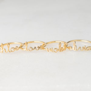 May include: Four gold rings with the words "Chloe", "Love", "Nicole", and "Olivia" written in cursive.