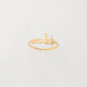 May include: A gold ring with the word "violet" written in cursive.