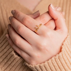 May include: A gold ring with the word "chloe" written in cursive script.