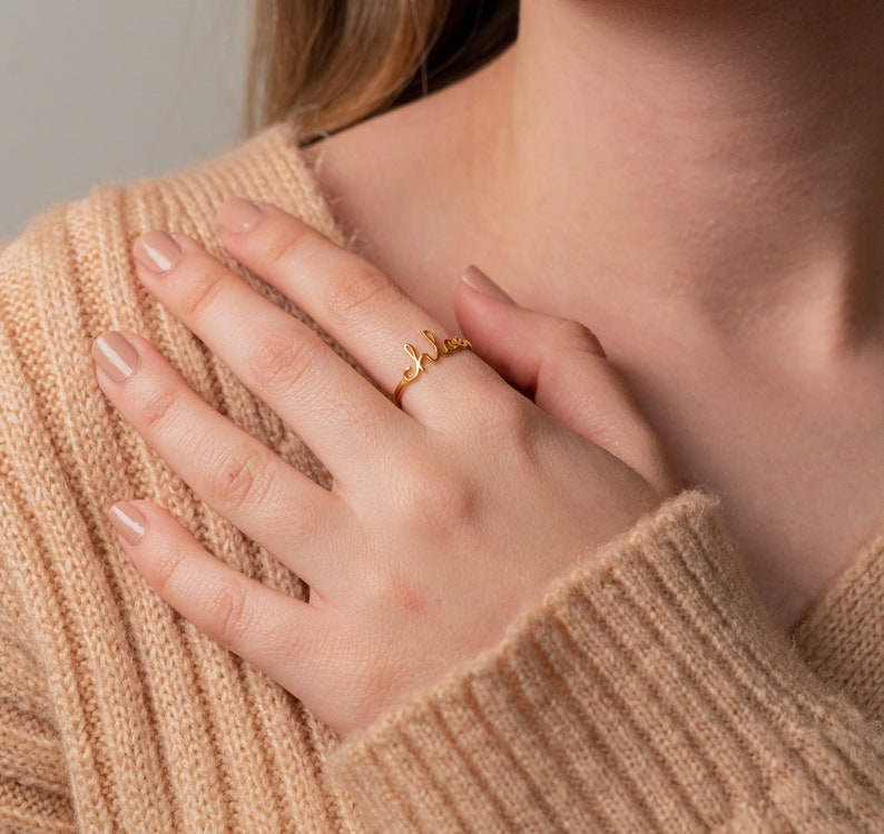 May include: A gold ring with the word "Chloe" written in cursive script.