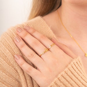 May include: A gold ring with the word "well" and "love" written out in cursive.