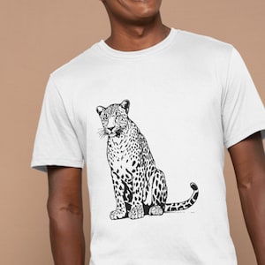 May include: A white t-shirt featuring a black and white illustration of a leopard sitting down.