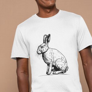 May include: A white t-shirt with a black and white illustration of a rabbit sitting on its hind legs.