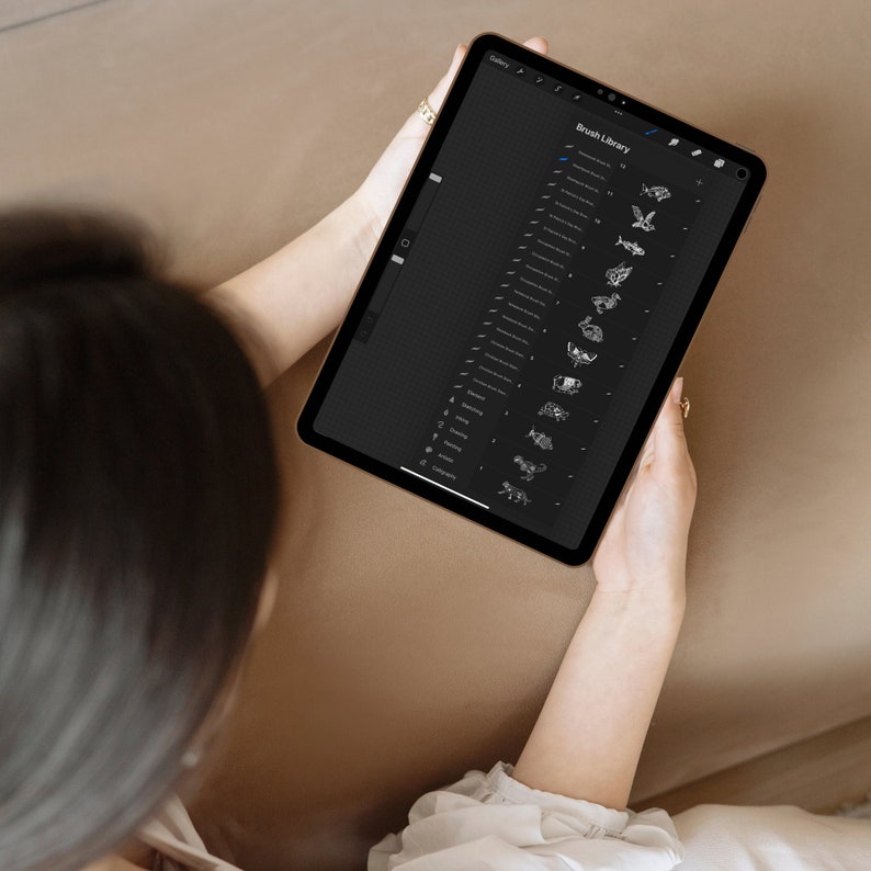 May include: A person using a digital tablet with a black screen displaying a list of brush options for a drawing app. The list includes names like "Chalk", "Pencil", "Watercolor", and "Ink".