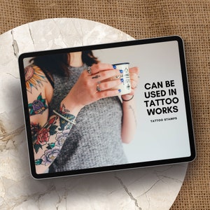 May include: A tablet screen displaying a woman with colorful tattoos on her arm holding a mug. The text on the screen reads "Can be used in tattoo works, Tattoo Stamps."