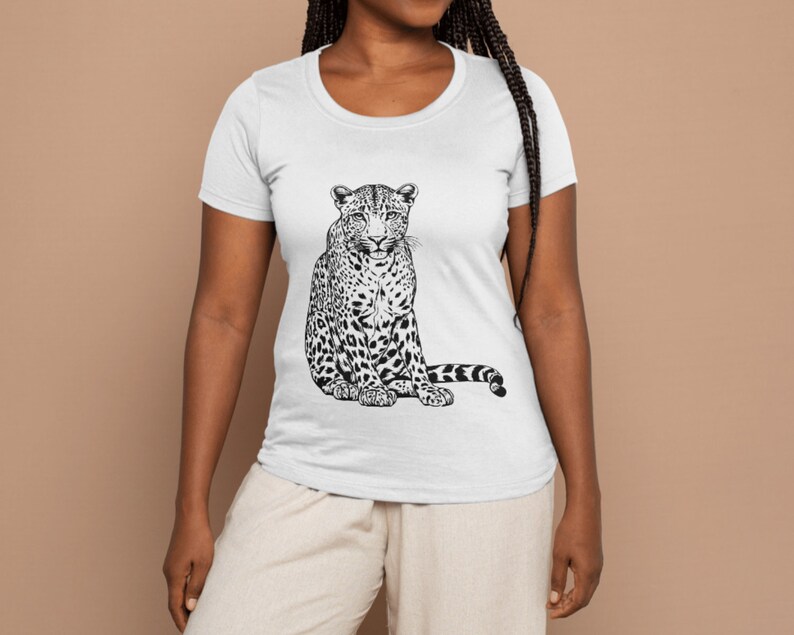 May include: White t-shirt featuring a black and white illustration of a leopard sitting down.