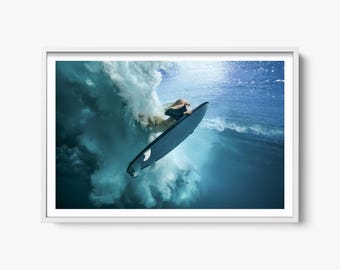 Può includere: Un surfista che cavalca un'onda sott'acqua. Il surfista indossa una muta da surf nera e tiene una tavola da surf. L'onda sta rompendo e l'acqua è turchese.