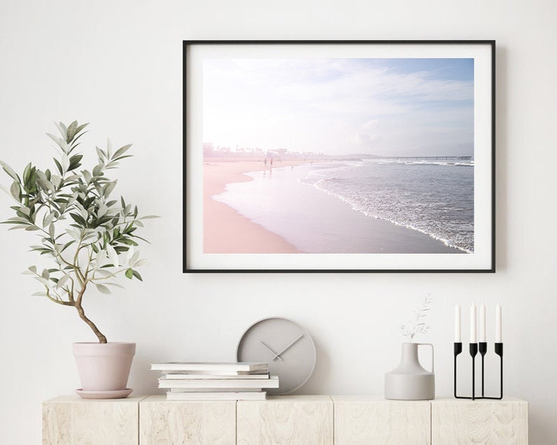 May include: A framed photograph of a beach scene with a soft pink and blue gradient sky and a wave crashing on the shore.