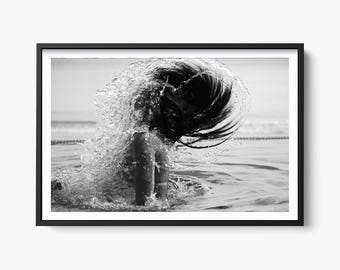 Può includere: Una fotografia in bianco e nero di una persona con i capelli lunghi che si tuffa in una piscina. L'acqua schizza intorno alla testa della persona, creando un effetto drammatico.