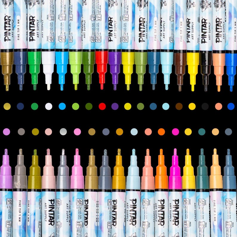 A set of fine-tip acrylic paint markers arranged in a row.