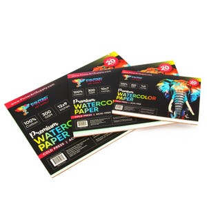 May include: Three different sizes of watercolor paper pads. The largest pad is 12x9 inches and features a colorful elephant design. The text on the pads reads "Pintar Art Supply", "100% Cotton", "300 GSM", "Premium Watercolor Paper", "Cold Press", and "Acid-Free".