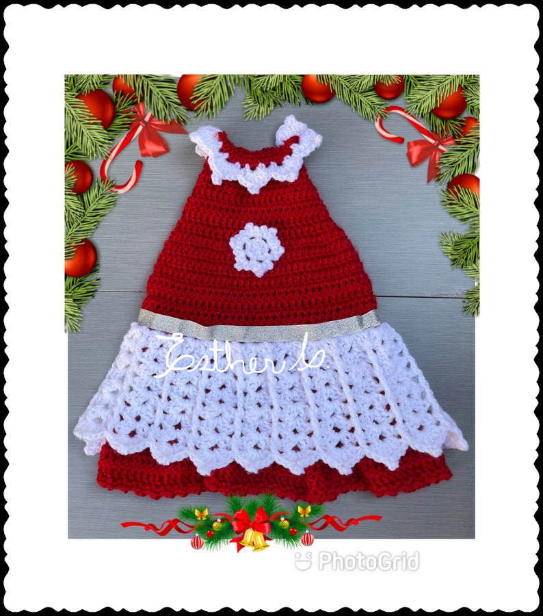 Puede incluir: Un vestido de crochet rojo y blanco con un dise&ntilde;o de copo de nieve y una cinta plateada. El vestido tiene un dobladillo festoneado y un escote con volantes.