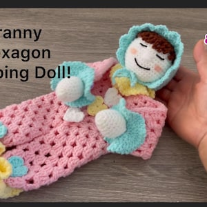 May include: A crocheted doll wearing a pink and blue outfit with yellow accents. The doll is lying on its back with its eyes closed, as if sleeping. The doll is labelled "Granny Hexagon Sleeping Doll!"