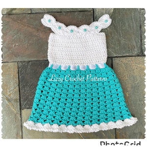 May include: A white and turquoise crochet baby dress with a white satin ribbon around the waist. The dress has a scalloped neckline and hemline with white beads.