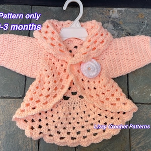 Puede incluir: Un patrón de cardigan de ganchillo para bebés de 0 a 3 meses. El cardigan es de color melocotón con un adorno de flor blanca. El patrón está disponible para su compra. "Lizzy Crochet Patterns" está escrito en la esquina inferior derecha de la imagen.