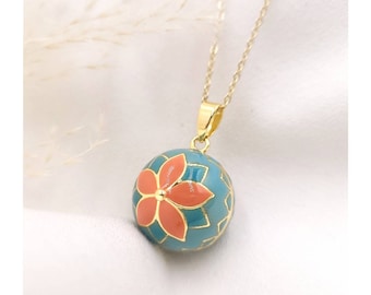 May include: A gold necklace with a teal and coral flower charm. The charm is a sphere with a delicate floral design.