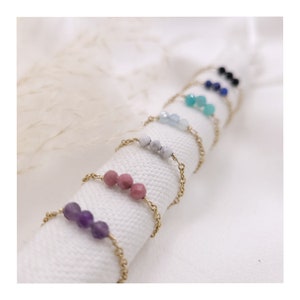 Peut inclure: Un ensemble de sept bagues délicates en chaîne dorée, chacune ornée de trois perles de pierres précieuses. Les bagues comprennent l'améthyste, le quartz rose, l'howlite blanche, l'aigue-marine, la turquoise, le lapis-lazuli et l'onyx noir.