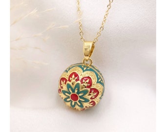 May include: Gold chain necklace with a round pendant featuring a green and red floral design.