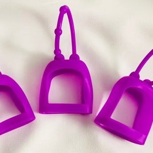 May include: Three purple silicone hand sanitizer holders with a loop handle. Each holder has a small opening for a hand sanitizer bottle.