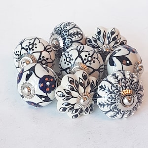 Peut inclure: Dix boutons de tiroir en céramique avec des motifs floraux noirs et blancs. Les boutons ont une base en métal argenté et sont parfaits pour ajouter une touche de charme vintage à n'importe quelle maison.