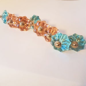 May include: A row of eight decorative glass knobs in two colours: light blue and amber. The knobs have a starburst design and gold accents.
