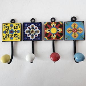 May include: Four decorative hooks with ceramic tile designs. The tiles feature colourful floral patterns in yellow, blue, red, and green. Each hook has a ceramic knob in a coordinating colour.