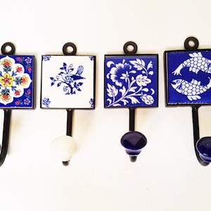 May include: Four decorative hooks with blue and white ceramic tiles featuring floral, bird, and fish designs. The hooks have black metal stems and blue, white, and black ceramic knobs.