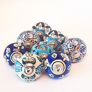 Könnte beinhalten: Eine Sammlung von zehn Keramik-Schrankknöpfen mit blauen, weißen und orangefarbenen Blumenmustern. Die Knöpfe haben eine silberne Metallbasis.