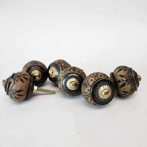 Może przedstawiać: Zestaw dekoracyjnych gałek do szafek. Gałki mają brązowo-czarny kwiatowy wzór z mosiężnymi akcentami. Jedna gałka ma śrubę. Idealne do mebli lub dekoracji wnętrz.