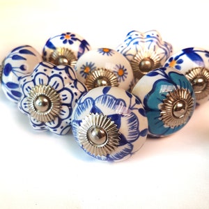 May include: A set of eight ceramic drawer knobs with blue and white floral patterns. The knobs have a silver metal base.