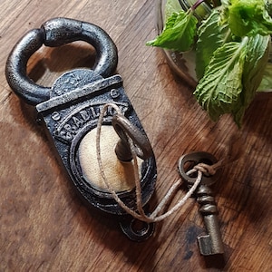 May include: A black cast iron padlock with a keyhole and a key attached to it with twine. The padlock has the word "GRABLOCK" embossed on it.