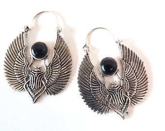 Puede incluir: Un par de pendientes de plata con una piedra negra en el centro de cada uno. Los pendientes tienen forma de pájaro con las alas extendidas.