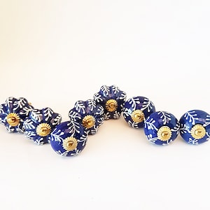May include: Set of ten blue ceramic drawer knobs with white floral designs and gold accents.