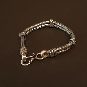 May include: A silver bracelet with a double-strand chain and a decorative clasp.