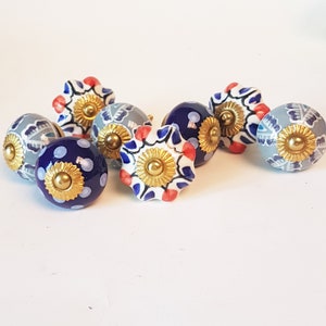 May include: A set of six ceramic drawer knobs with a blue, white, and red floral pattern. The knobs have a gold-colored metal base.