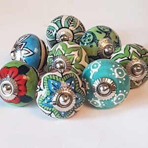 May include: Assortment of colourful ceramic cabinet knobs with intricate patterns and silver accents. The knobs feature a variety of colours, including blue, green, red, and white.
