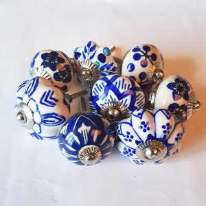 Peut inclure: Un ensemble de huit boutons de cabinet en céramique bleu et blanc avec des motifs floraux complexes. Les boutons ont une base en métal argenté et sont parfaits pour ajouter une touche d'élégance à tout décor de maison.