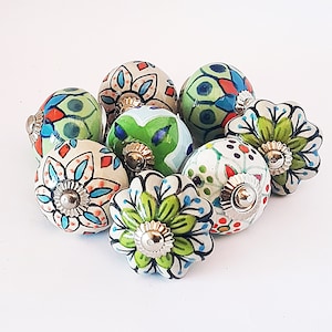 May include: A set of ten colourful ceramic knobs with floral and geometric patterns in shades of green, blue, red, and white. The knobs have a shiny finish and are perfect for adding a touch of whimsy to cabinets, drawers, or furniture.