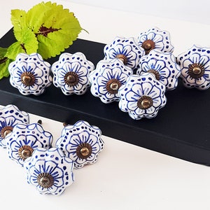 Könnte beinhalten: Ein Satz von 10 blauen und weißen Keramik-Schrankknöpfen mit Blumenmuster. Die Knöpfe haben eine goldfarbene Metallbasis.