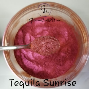 May include: A close-up of a spoon scooping out a red glitter powder from a clear jar. The jar has a brown lid and the text "GlitterandCrafts4U.com" is printed on the lid. The text "Tequila Sunrise" is printed below the jar.