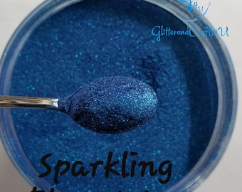 Puede incluir: Primer plano de un tarro de purpurina azul agua brillante. La purpurina es de un color azul intenso con un ligero brillo. El tarro está etiquetado con "Sparkling Blue Water" y "GlitterandCrafts4U".