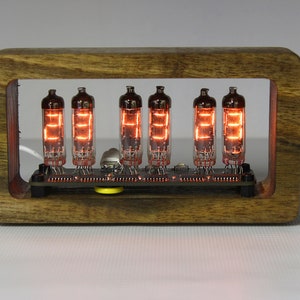 Könnte beinhalten: Eine digitale Uhr mit sechs leuchtend orangefarbenen Elektronenröhren in einem Holzrahmen. Die Röhren, die auf einer Leiterplatte montiert sind, zeigen leuchtende Ziffern an. Die Uhr hat eine warme, Vintage-Ästhetik.