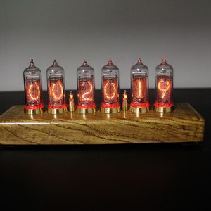 May include: A wooden base with six clear glass Nixie tubes displaying the number "02019". The tubes are lit with a bright orange glow.