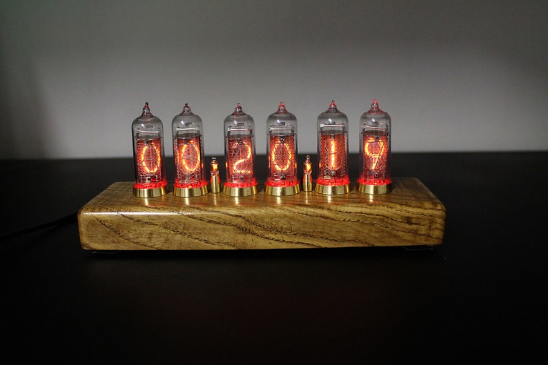 May include: A wooden base with six clear glass Nixie tubes displaying the number "02019". The tubes are lit with a bright orange glow.