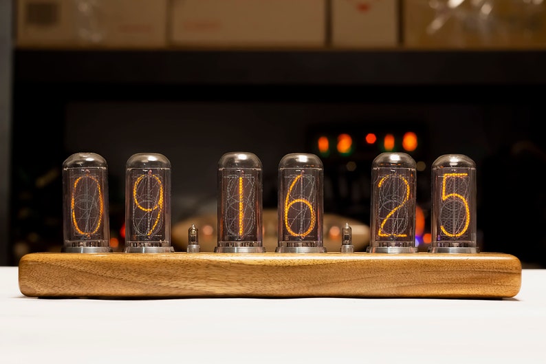 Puede incluir: Un reloj de madera con seis tubos Nixie naranjas brillantes que muestran la hora 09:16:25.
