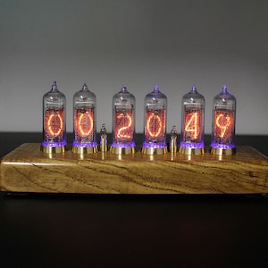 May include: A wooden clock with six clear glass tubes displaying the time as 002049. The tubes have orange glowing numbers and purple glowing lights at the bottom.